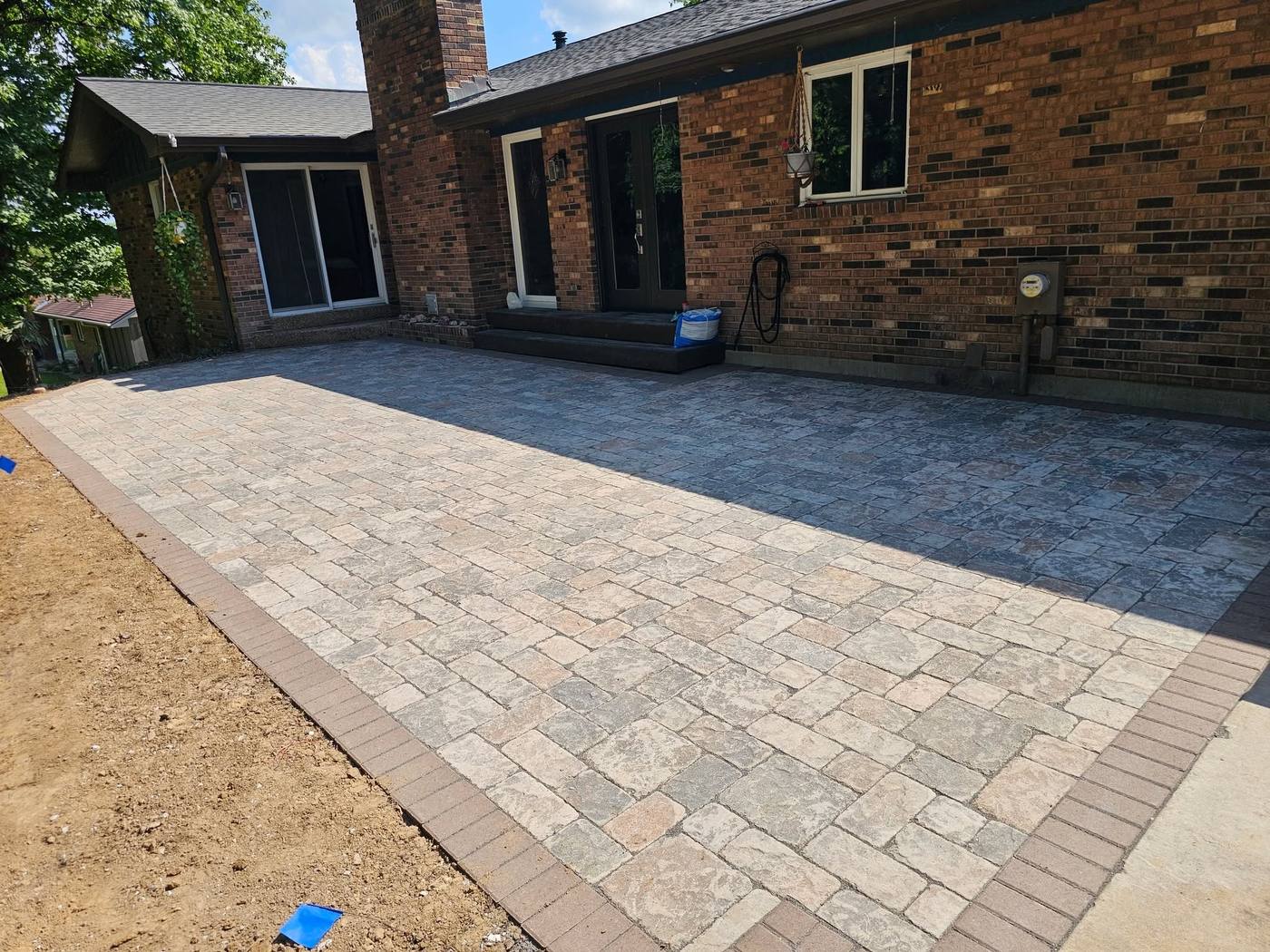 Paver patio with a border along a brick house