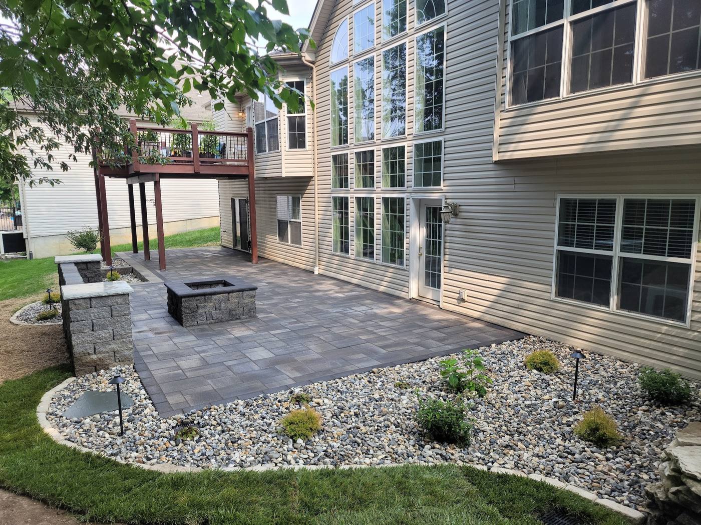 Patio with a fire pit, seating-wall pillars and a planted rock border