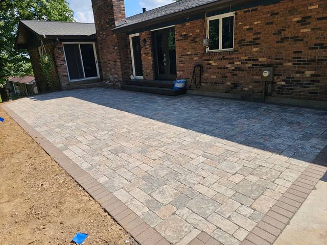 Paver patio with a border along a brick house