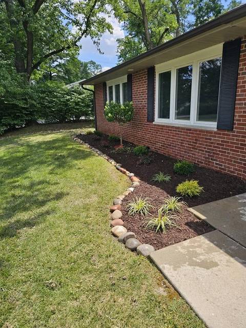 Fresh mulch bed with a river-rock edge along a brick house
