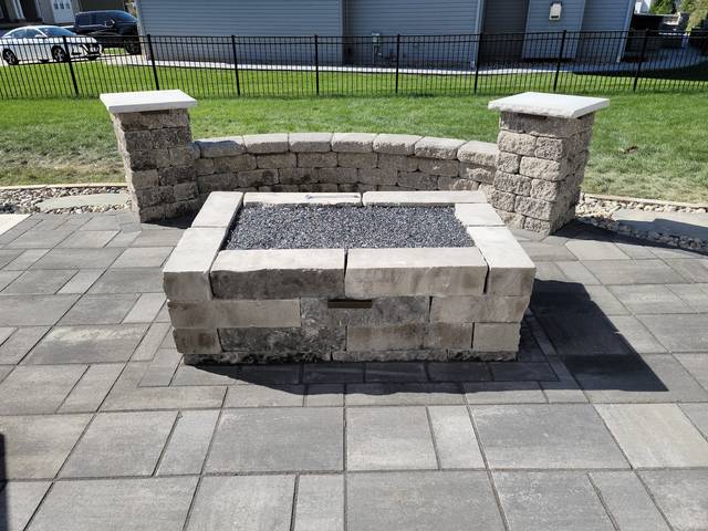 Square fire pit inside a curved seating wall with pillars