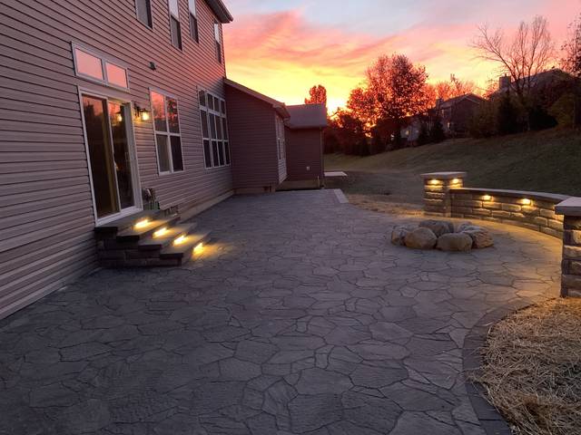 Flagstone-look patio at sunset, lit steps and a lit seating wall